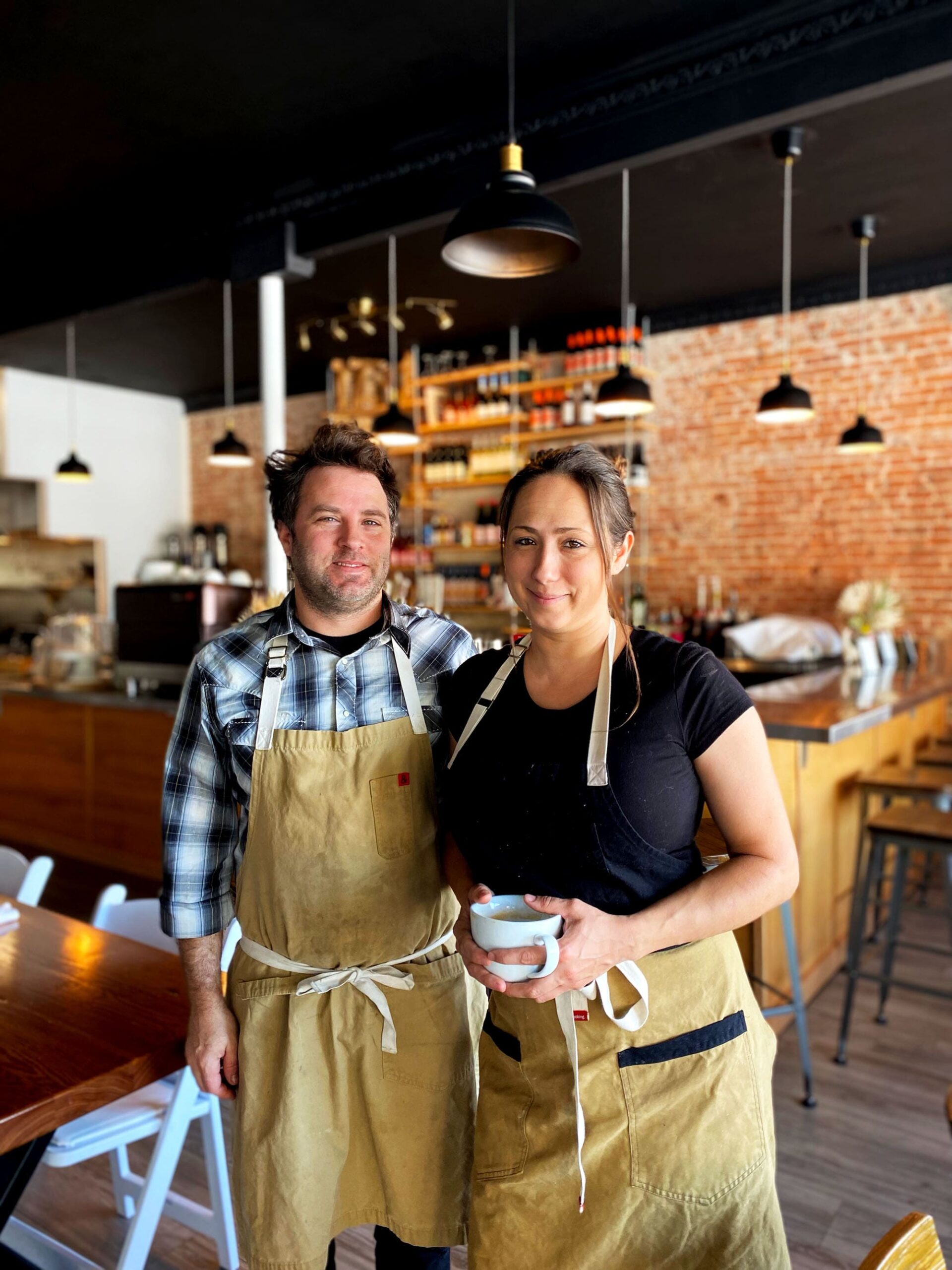 Chef/Owners Sarah Heard and Nathan Lemley standing together smiling in their restaurant, Commerce Cafe.
