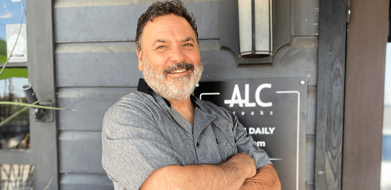Chef/Owner Christian Mertens standing and smiling in front of his restaurant, ALC Steaks, in Austin, Texas.