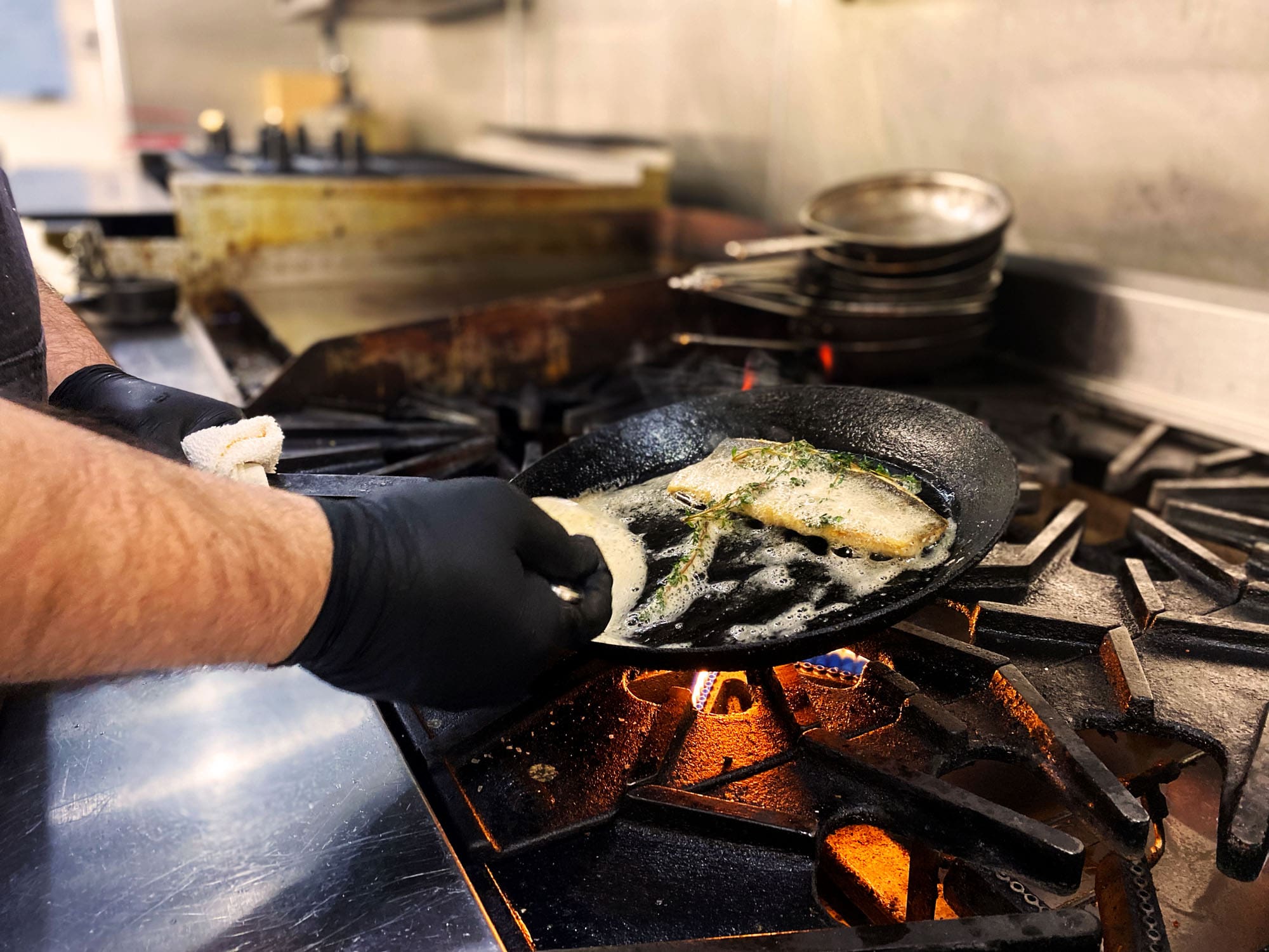 Chef Patrick Dunlop searing trout in a cast iron skillet over a flame.