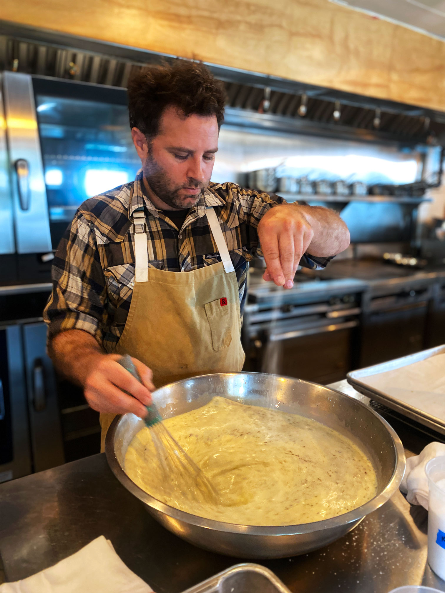 Chef Nathan Lemley adding pepper to the batter in the kitchen of Foreign and Domestic